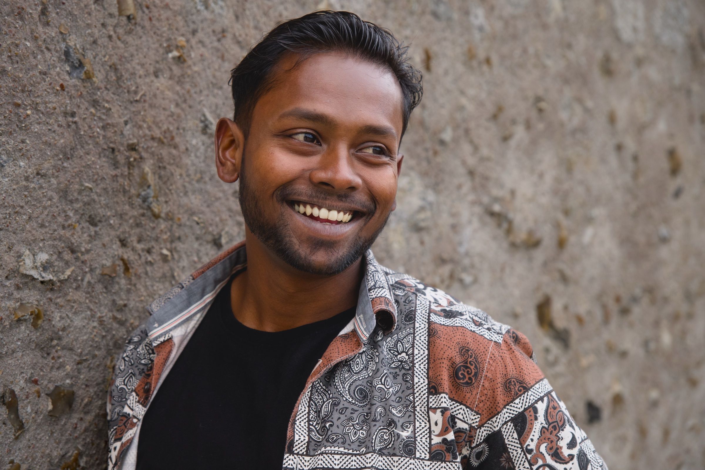 Smiling man by a stone wall