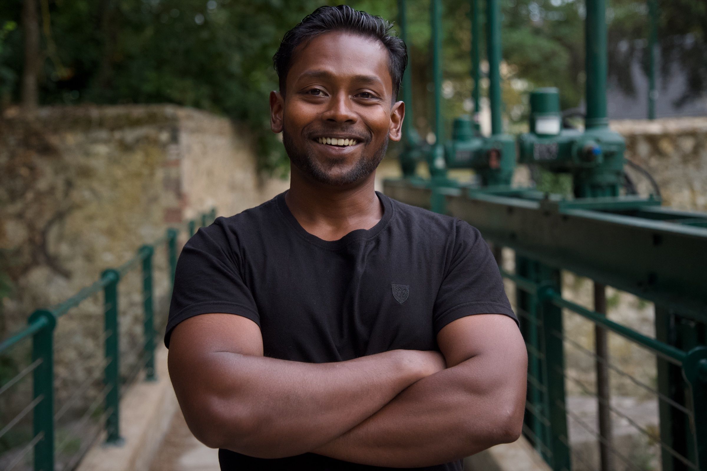 Man with arms crossed by a green railing